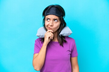 Young caucasian woman with Inflatable Travel Pillow isolated on blue background having doubts and with confuse face expression