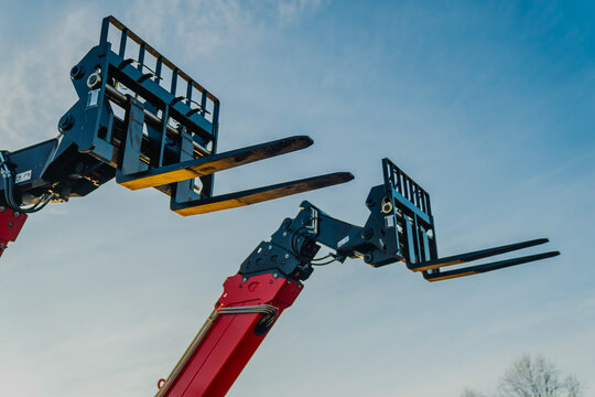 Two construction telehandler fork attachments raised as lifts up in the air