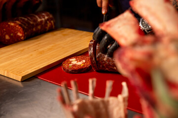 Slaughterhouse worker slicing handmade sausage in a butchers kitchen. Male hands placing a sausage on the cutting table.