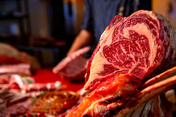 Multiple raw and seasoned meat goods set of on a wooden board and metal table. Butchers hands slicing steaks from raw pork meat. Man hands cutting pieces of pork meat for barbecue.