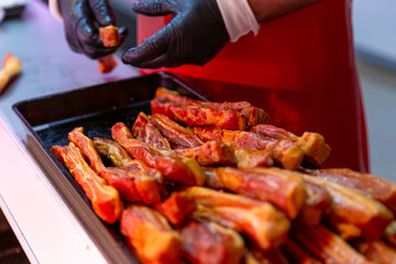 Male worker hands arranging meat loins on tupperware ready to be sold in market. Meat chops on display. Food industry content.
