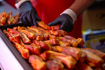 Butchers hands arranging meat products on tray for display cabinet at shop. Male placing slices of meat in fulfilling tupperware. Food industry.