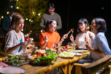 A group of women are sitting around a wooden table, eating food and laughing