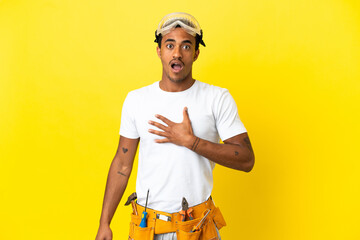 African American electrician man over isolated yellow wall surprised and shocked while looking right