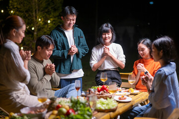 A group of people are gathered around a table with food and drinks