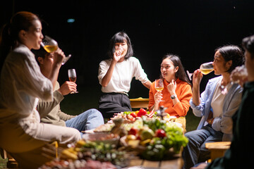 A group of people are sitting around a table with food and drinks