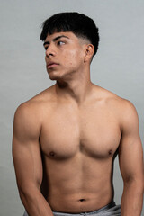 Fototapeta premium Muscular young man posing shirtless in studio setting, showing his physique