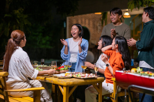 A group of people are gathered around a table with food and drinks