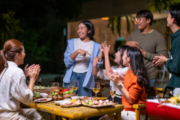 A group of people are gathered around a table with food and drinks