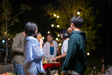 A group of people are gathered around a barbecue, enjoying each other's company
