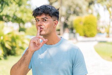 Fototapeta premium Young hispanic man at outdoors With glasses and doing silence gesture