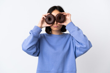 Young caucasian woman isolated on white background holding donuts in eyes with sad expression