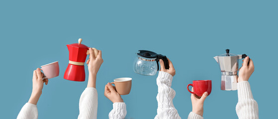 Female hands holding different coffee makers and cups on blue background