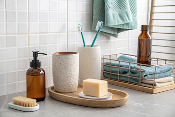 Naklejka premium Bathroom essentials soap, toothbrush holder, towels, and dispenser on a countertop.