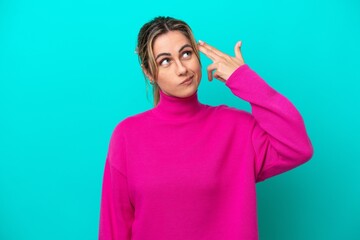 Young caucasian woman isolated on blue background with problems making suicide gesture