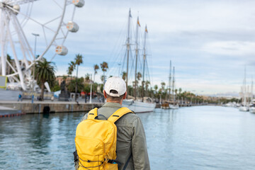 Man with yellow backpack on the promenade of the port of Barcelona