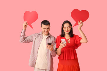 Young couple with mobile phones and speech bubbles on pink background. Online dating
