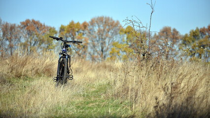 bike stands on in the field. A mountain bike stands on a field path with dry autumn grass. cycling. Mountain bike. outdoor cycling activities. active rest, sports, travel. space for text