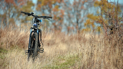 bike stands on in the field. A mountain bike on a field path with dry autumn grass. cycling. outdoor cycling activities. active rest, sports, travel. good for health. recreation, warm season