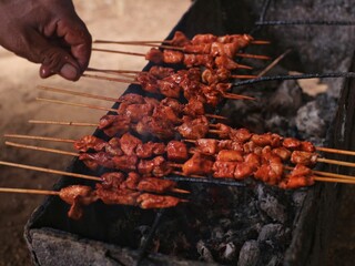 Someone is grilling satay over hot coals, a typical Indonesian satay dish