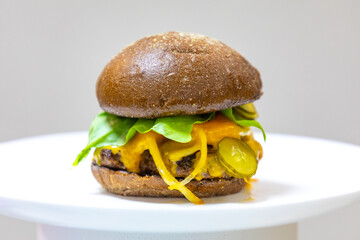 Traditional rustic burger sandwich with cheddar cheese, vegetables and Australian bread in creative photography and cozy village setting