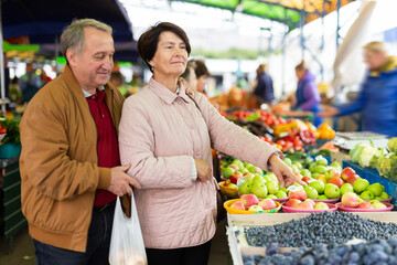 Man and woman customers buying berries in open-air market