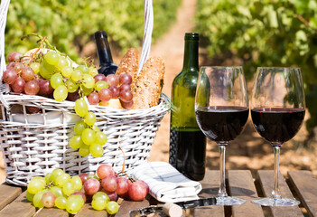 Still life with glass of red wine grapes and picnic basket on table