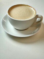 White cup with coffee on a white table. Coffee in a white cup