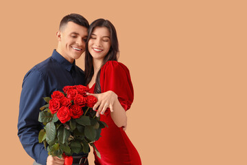 Young engaged couple with wedding ring and bouquet of roses on beige background. Valentine's Day celebration