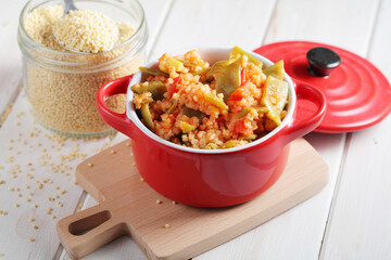 Millet porridge with green beans and tomato in red pot
