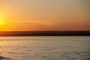 Sunset casts golden hues on the Vilga river, creating a peaceful atmosphere that reflects natures charm.