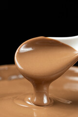 Melted milk chocolate poured out of a spoon.