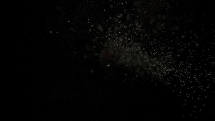 Many dust particles floating falling from top in light on empty black background with spotlight from above.