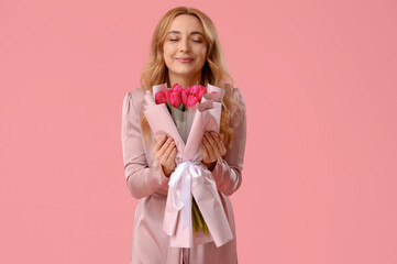 Portrait of beautiful middle-aged woman with bouquet of flowers on pink background. International Women's Day