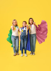 Obraz premium Little girls dressed as superheroes with gold ribbons on color background. Childhood cancer awareness concept