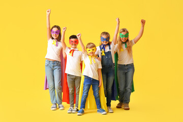 Little children dressed as superheroes with gold ribbons on color background. Childhood cancer awareness concept