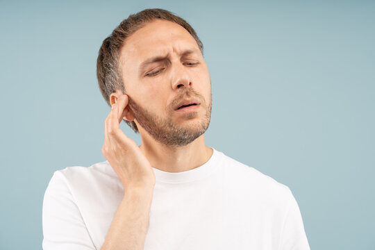 Unwell man feels discomfort in ear stuffiness, mild hearing loss. Male suffers pulling, sharp pain, sensitivity to sound by ear infections, fluid buildup, sinus congestion, inflammation, nerve damage.
