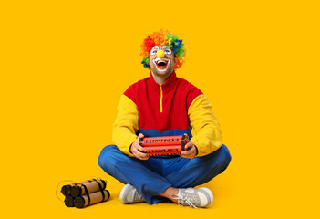 Young man as laughing crazy clown with dynamite sitting on yellow background