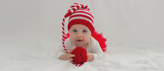 Christmas portrait of a cute little newborn baby girl wearing a Santa Claus hat or knitted cap.