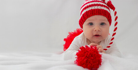 Christmas portrait of a cute little newborn baby girl wearing a Santa Claus hat or knitted cap.