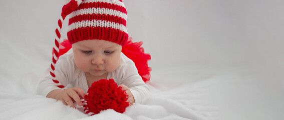 Christmas portrait of a cute little newborn baby girl wearing a Santa Claus hat or knitted cap.