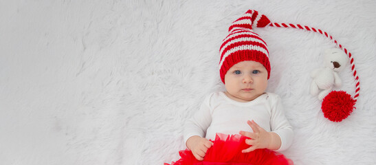 Christmas portrait of a cute little newborn baby girl wearing a Santa Claus hat or knitted cap.