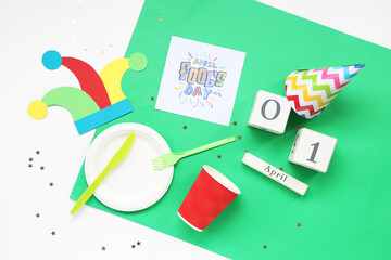 Table setting with festive postcard, calendar and party decor for April Fools Day on color background