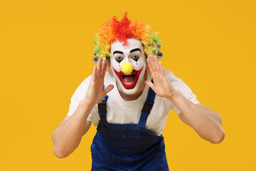 Screaming young man as clown in jumpsuit on yellow background