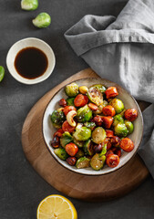 Brussels sprouts with chorizo ​​sausages, nuts and sesame seeds. Concept nutritious asian dish in a bowl on a wooden board