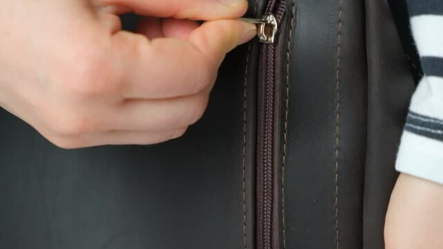 Zipping up plastic zipper on leather backpack slow motion