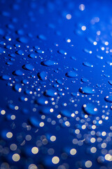 A vibrant blue background adorned with an abundance of water drops