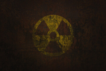 Radioactive (ionizing radiation) round yellow and black danger symbol painted on a massive rusty metal wall with dark rustic grunge texture background. Nuclear, radioactive alert concept.