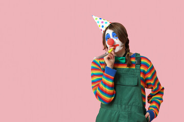 Young woman dressed as sad clown with whistle on pink background. April Fool's day celebration