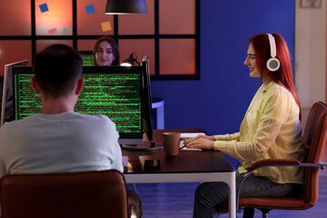 Young female programmer working with computer in office at night